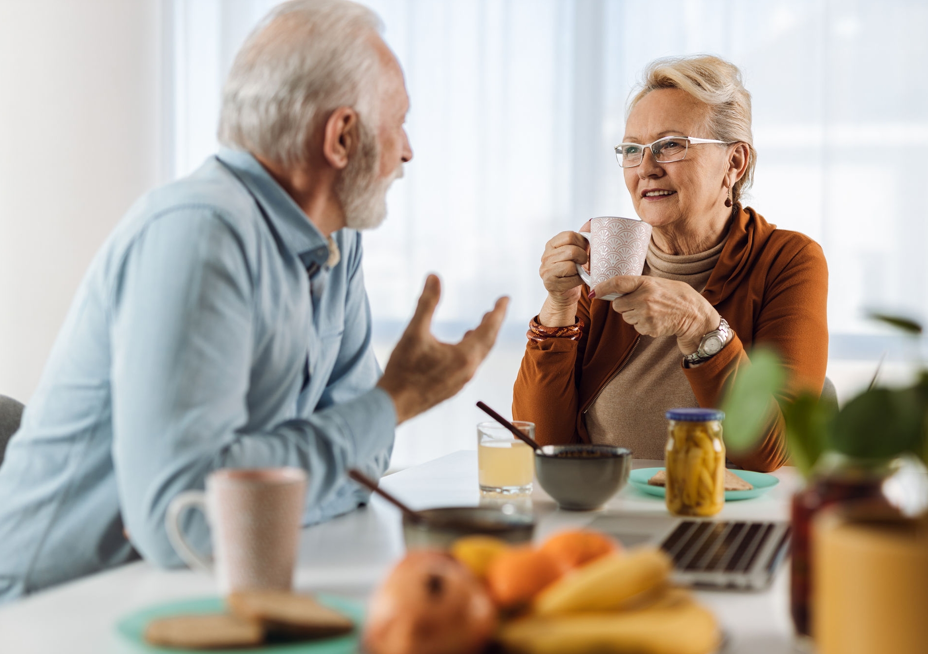 Happy mature couple communicating while having breakfast at dining table.