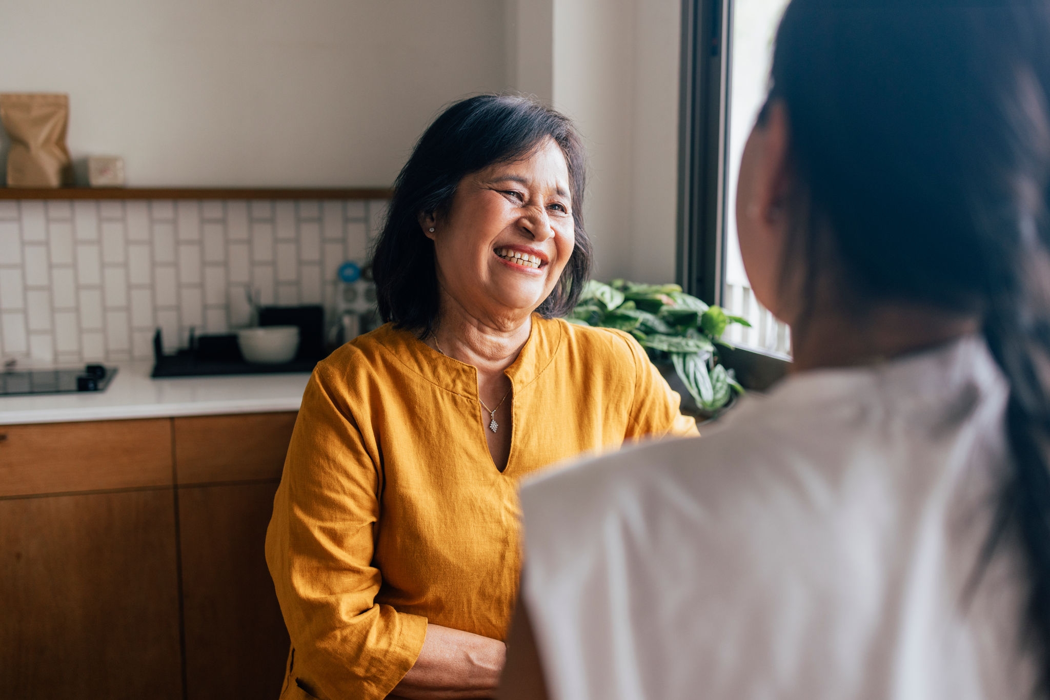 A smiling Asian female spending her leisure time with her anonymous daughter.