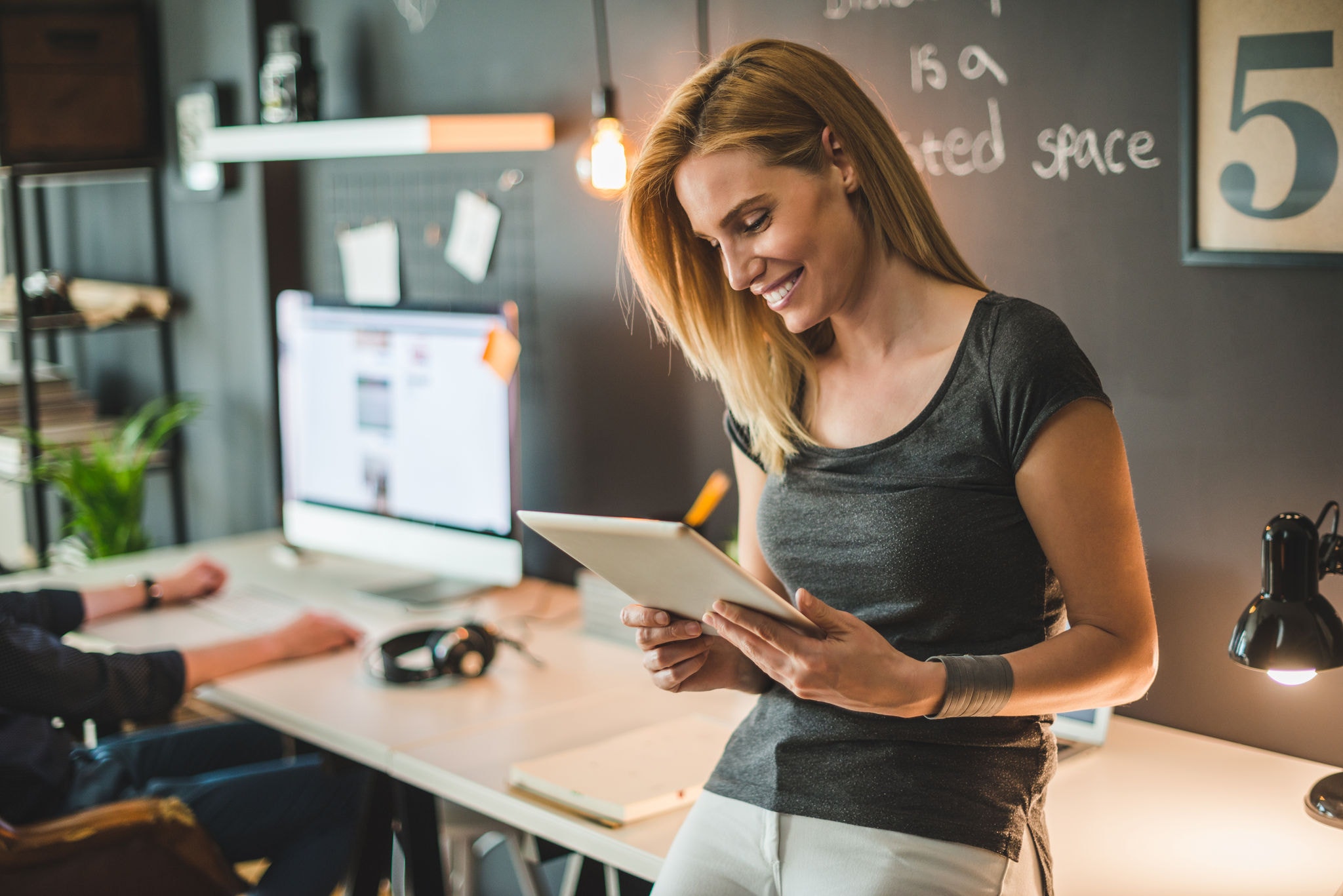 A woman in a modern office focused on her tablet.