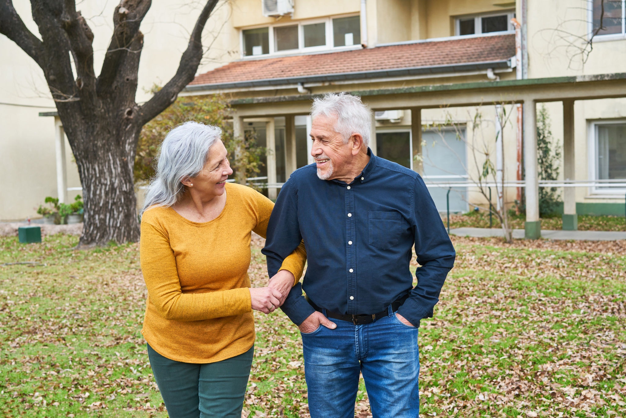 Happy couple walking together in garden of nursing home during autumn