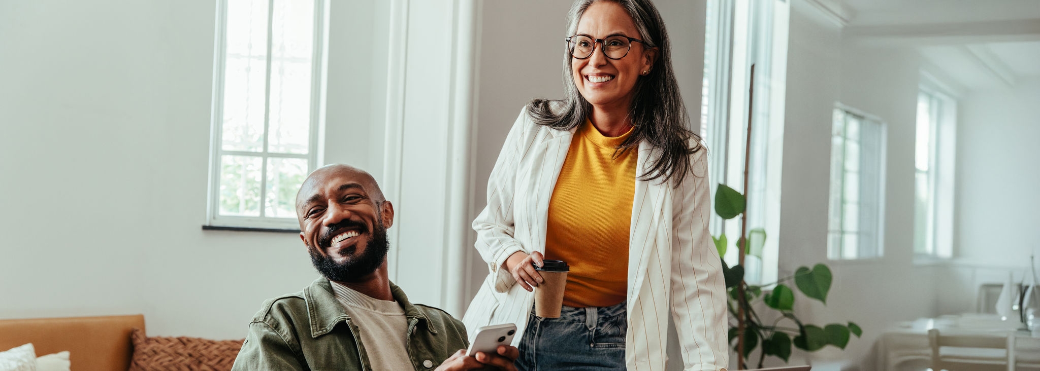 Colleagues having a casual discussion in a co-working office environment, featuring a smiling manager and a relaxed atmosphere.