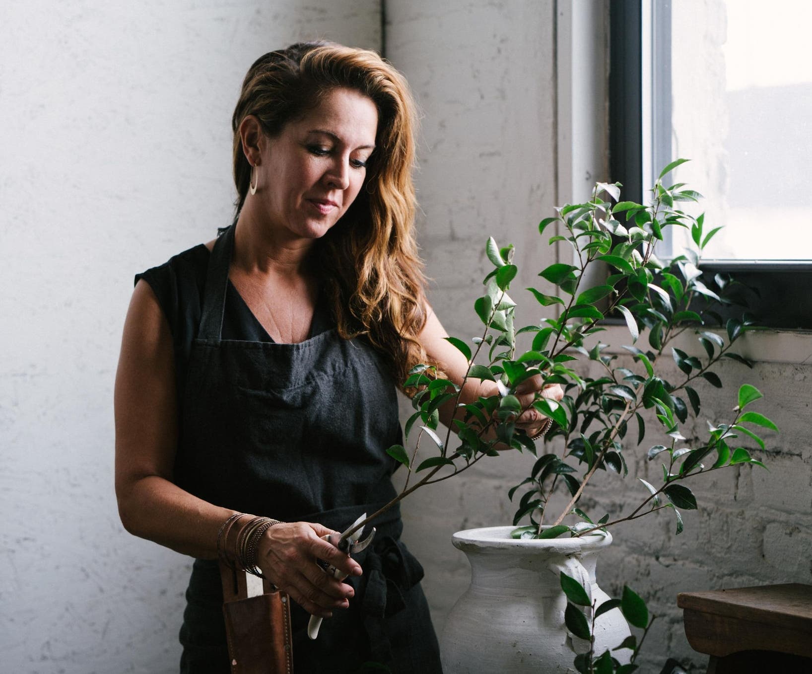 Female florist trimming branches in her flower shop