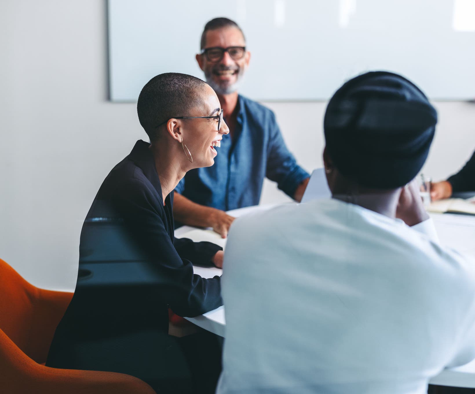 Happy businesspeople smiling cheerfully in a meeting room. Group of successful businesspeople sitting together during their morning briefing in a modern office. Colleagues working together.