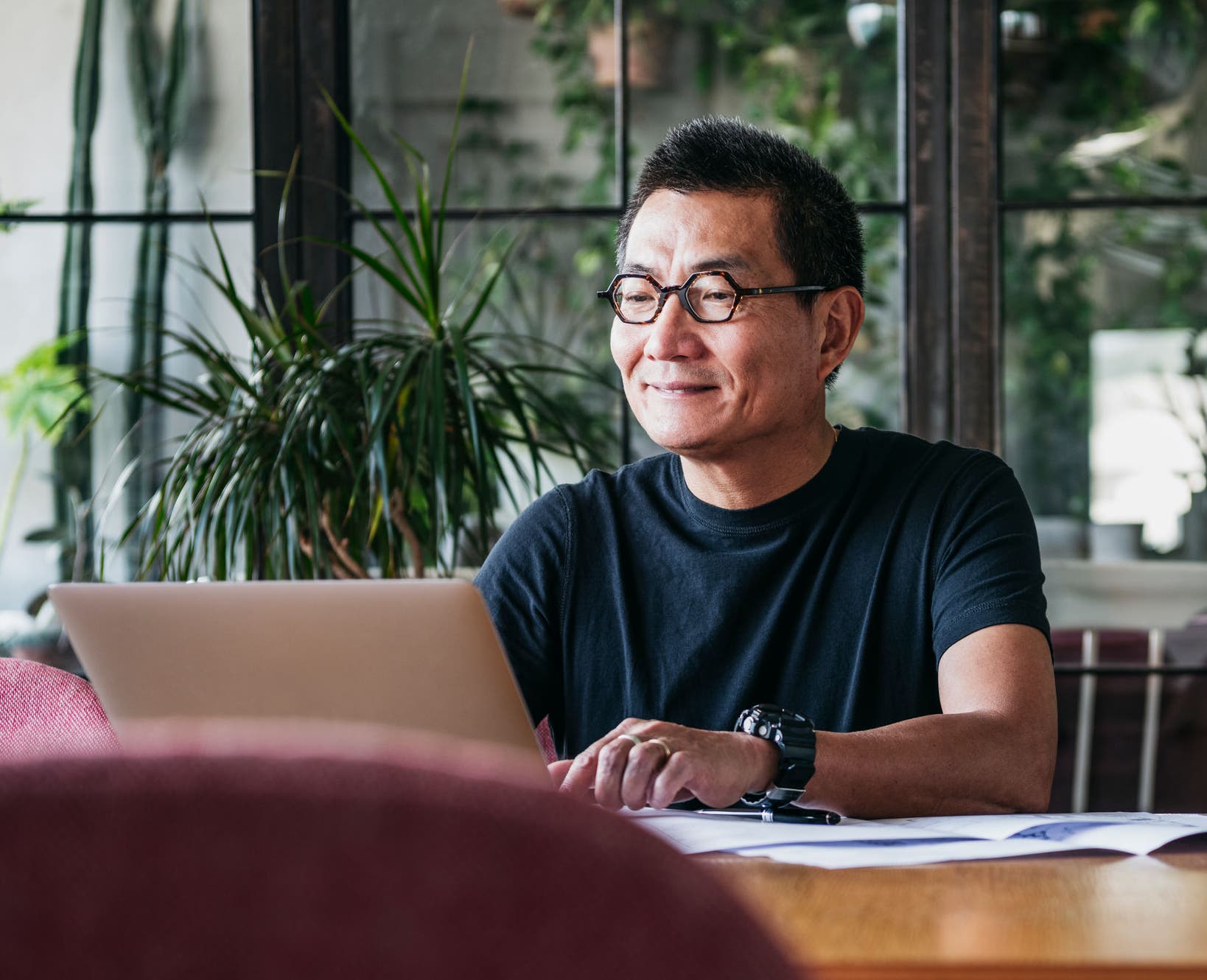 Mature man in glasses at home, typing on computer, contented, small business owner