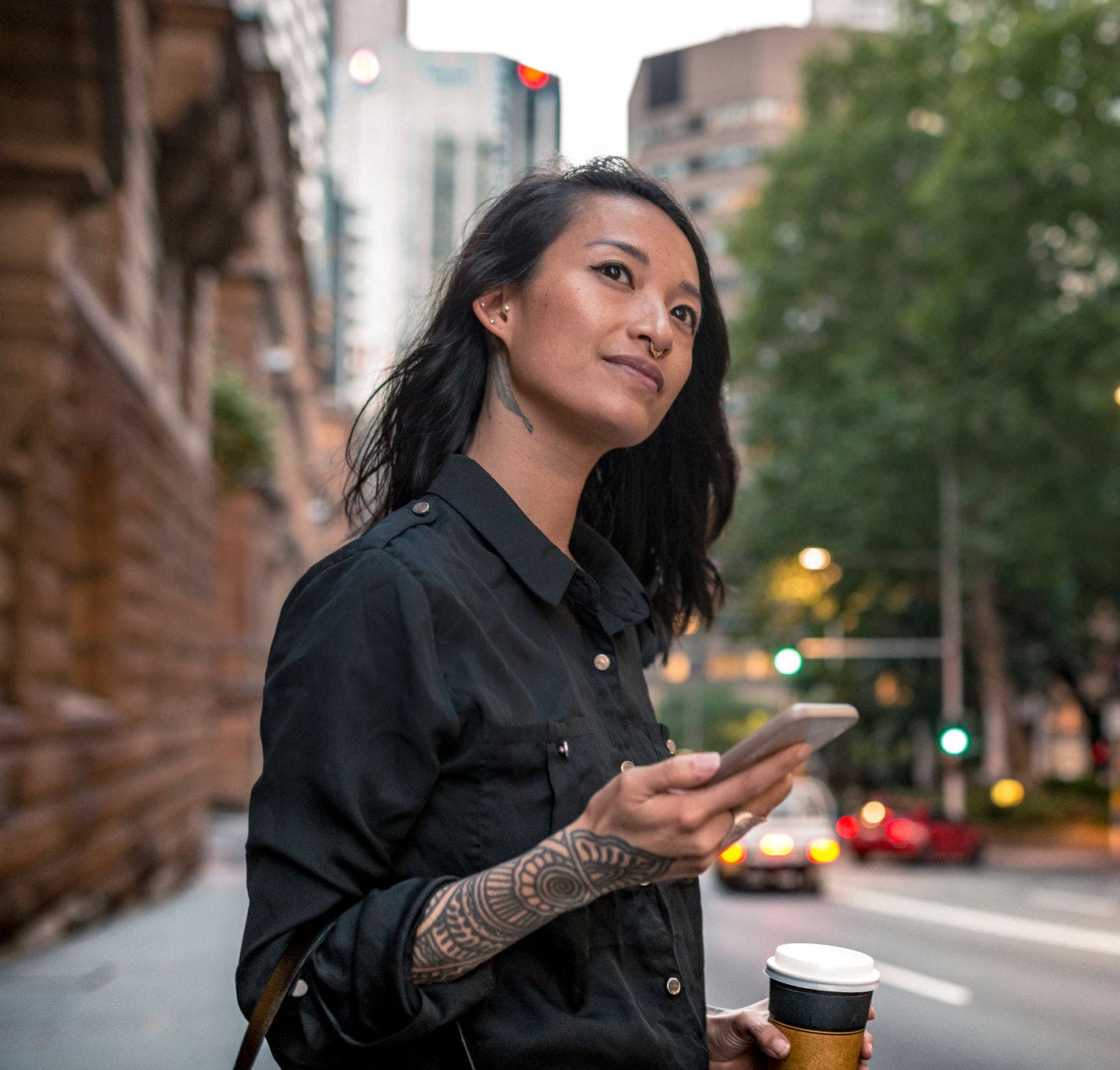 Young businesswoman waiting for taxi in Sydney. She has a coffee to go.