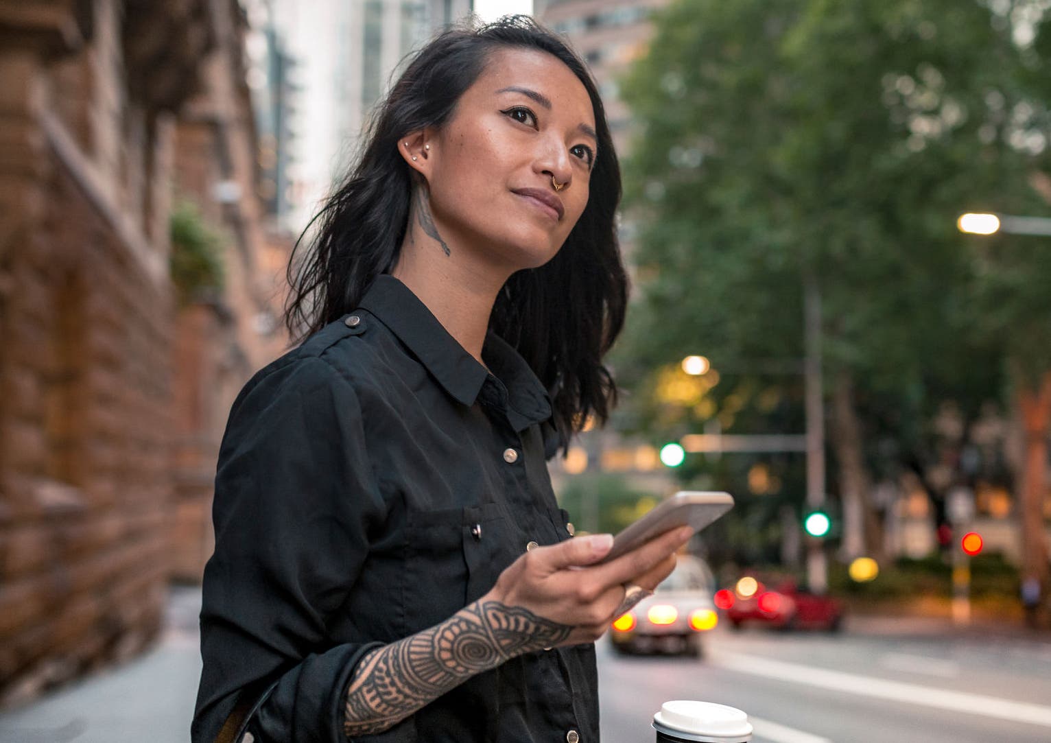 Young businesswoman waiting for taxi in Sydney. She has a coffee to go.
