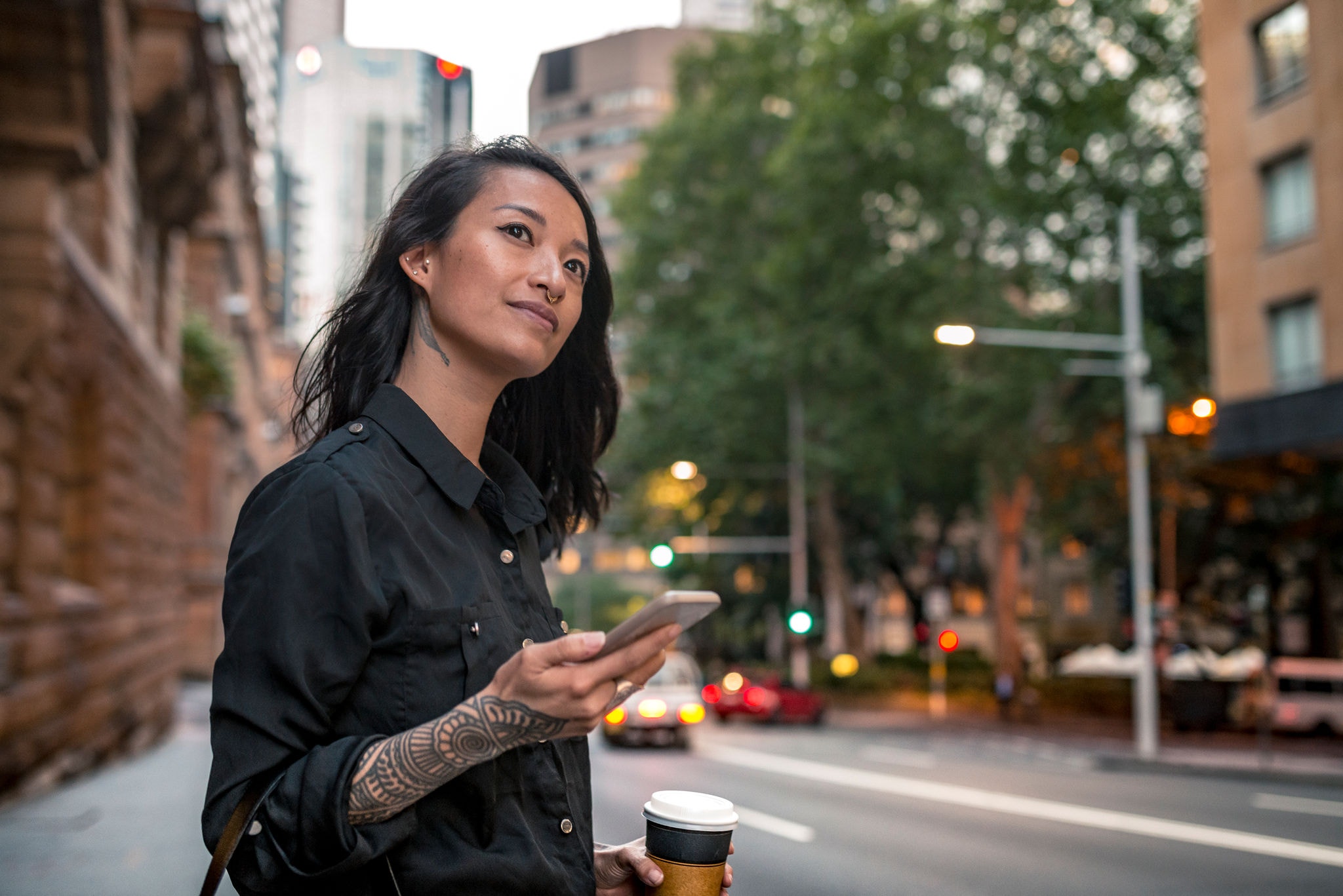 Young businesswoman waiting for taxi in Sydney. She has a coffee to go.