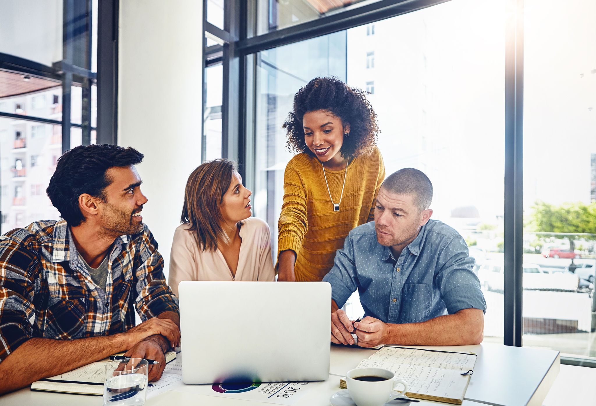 Group of colleagues gathered around a laptop in a modern office