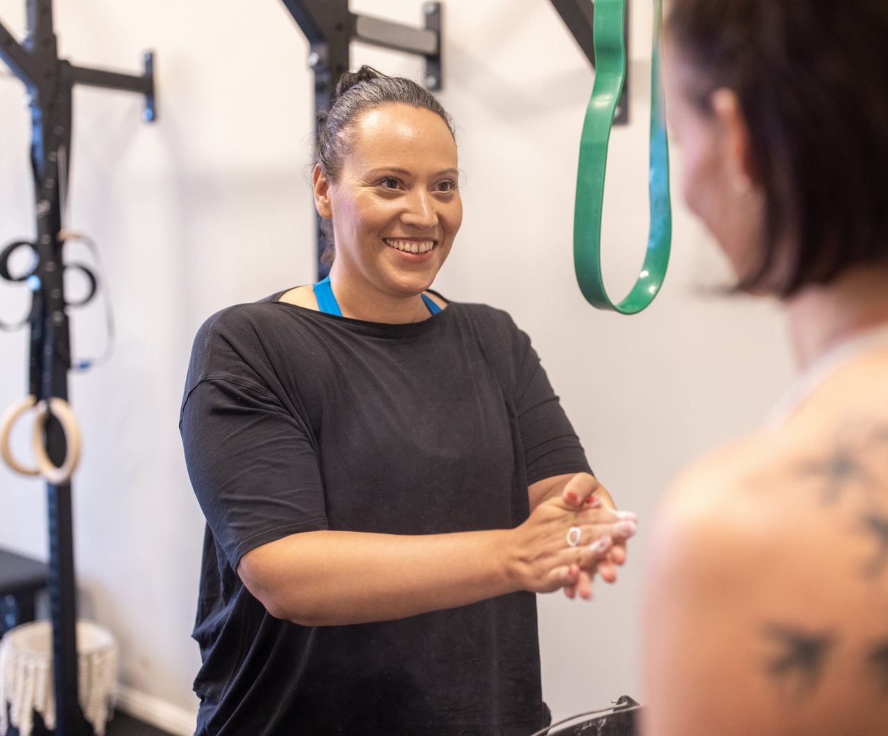 Healthy mid adult woman with her personal trainer in fitness studio. Smiling woman in sportswear talking with her fitness instructor at gym.