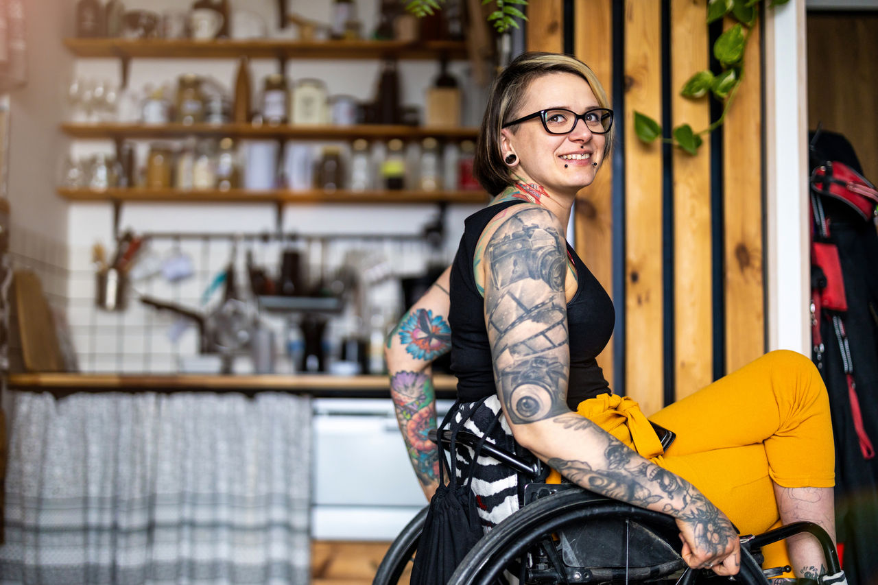 Portrait of an young tattooed woman in a wheelchair at home