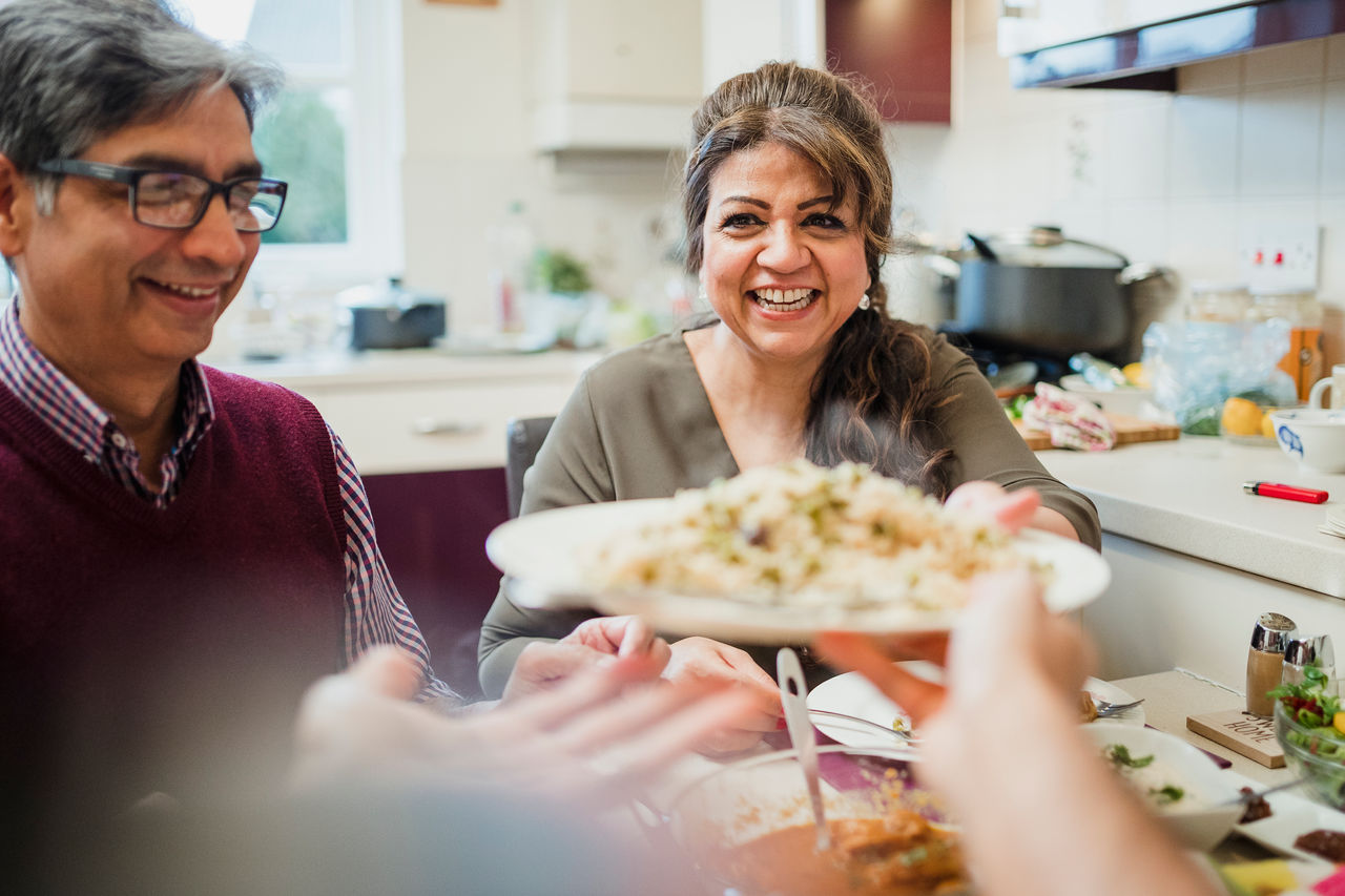 Mother passing a serve of curry and rice to her son at dinner